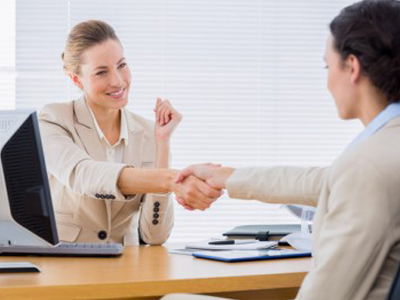 Smartly dressed young women shaking hands in a business meeting at office desk featured