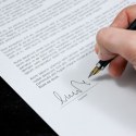 A shot of an individuals hand signing their name with a fountain pen