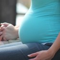 A pregnant woman sitting down and holding hands