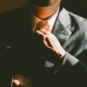Man straightening tie when wearing a suit