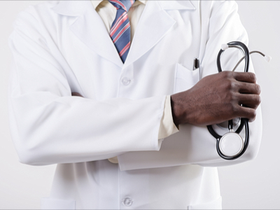 Arm and hand of a black doctor in a white lab coat holding an instrument