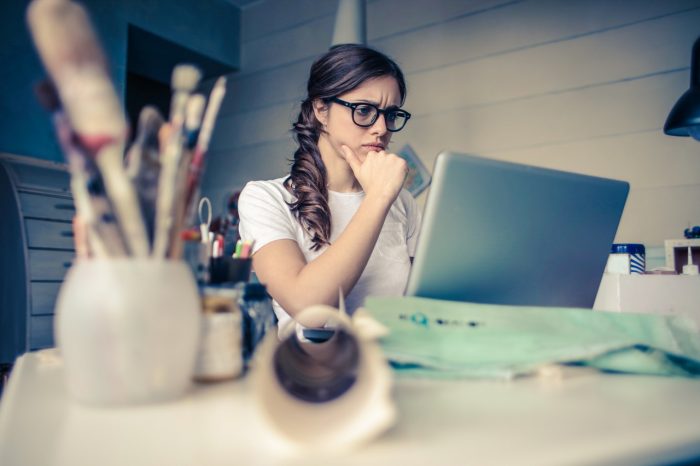 Woman sitting at laptop thinking, job hunting