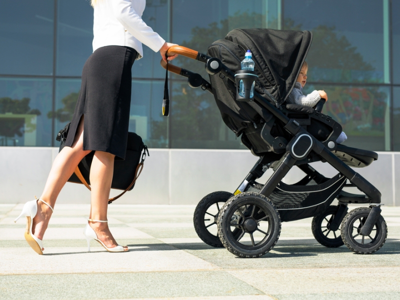 Business mother pushing baby on the way to work, working mum