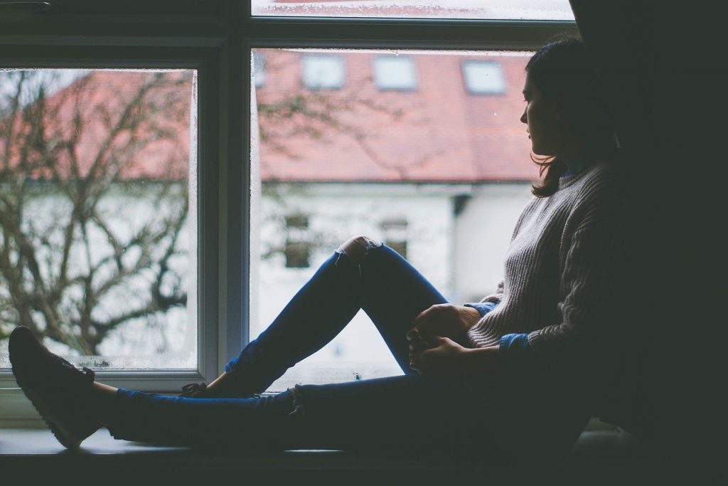 young woman looking out of window, sad, coronavirus, stress