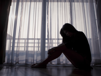 Sad woman sitting alone near window, human trafficking
