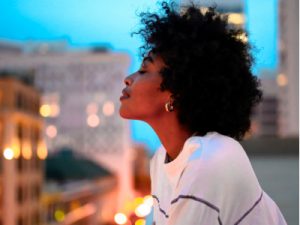 black woman looking out from balcony, wellbeing