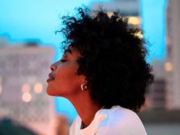 black woman looking out over balcony, wellbeing, relax