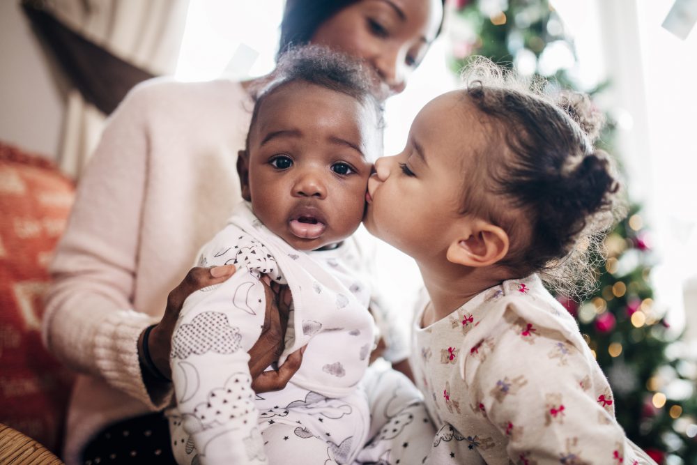 Little Girl Kissing her Baby Cousin, Refuge Christmas campaign
