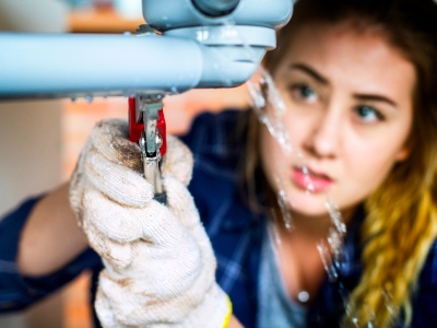 Woman fixing kitchen sink, Female Plumber, Women in plumbing featured