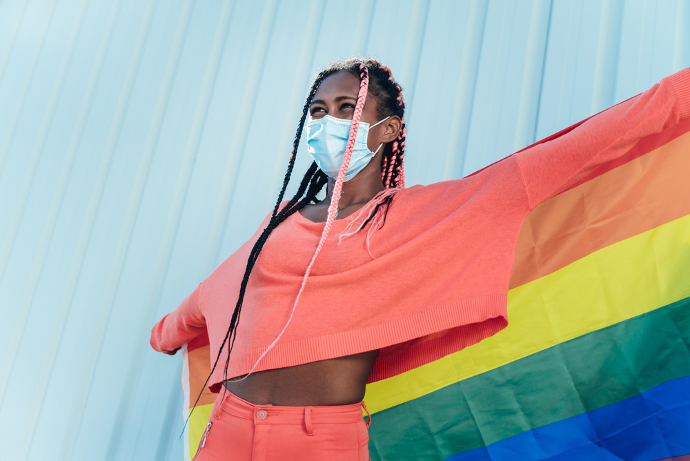young gay black woman holding pride banner, LGBTQ