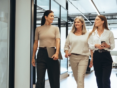 Three cheerful businesswomen walking together in an office, female leaders