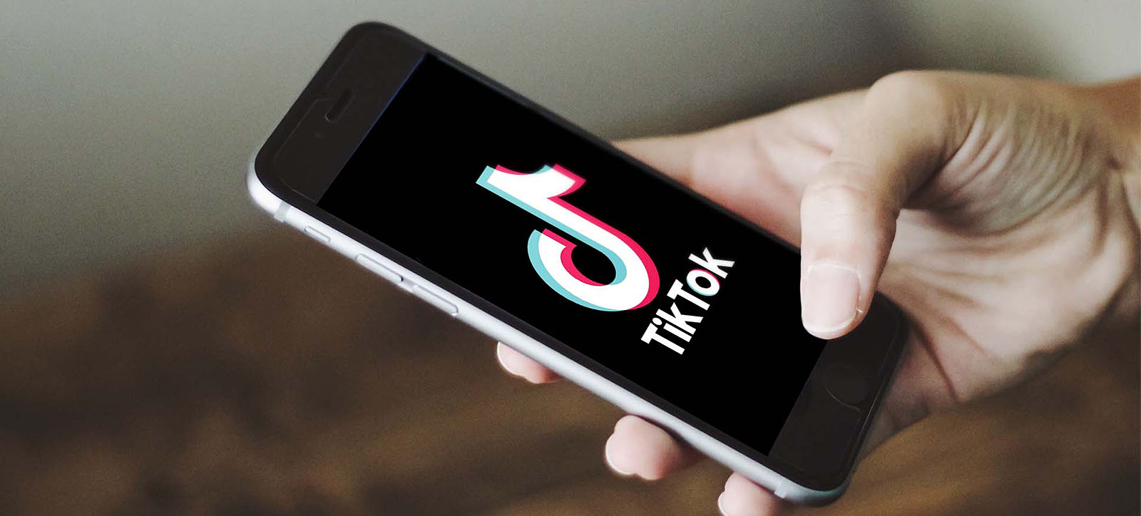 Man holding a smartphone with TikTok app open