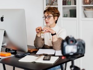 Confident elegant lady in eyeglasses hosting webinar