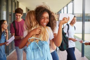 Two girls celebrating exam results in school corridor