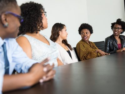 Diversity and inclusion, five colleagues sitting at table during meeting