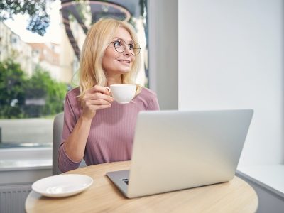 Happy mature woman sitting at computer, working at home