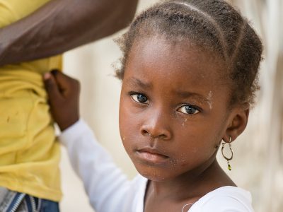 Portrait of African black little girl looking at camera and holding dad's shirt