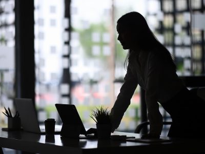 Businesswoman leaning over desk in office, working in property