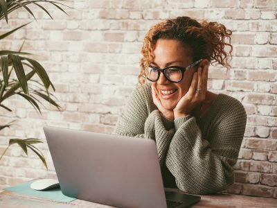 Happy woman working from home, using imposter syndrome to her advantage