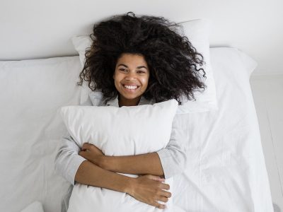 Smiling happy woman hugging pillow after having good night's sleep