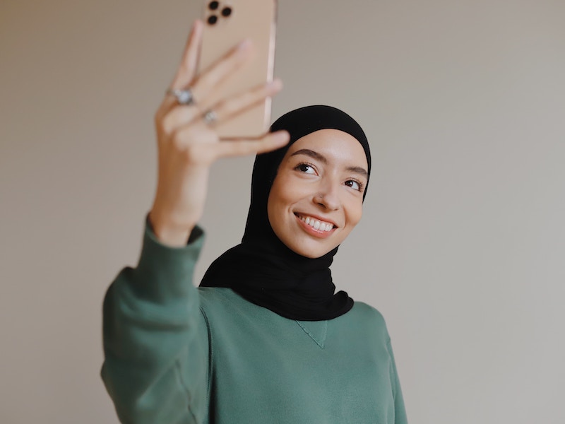 Smiling woman taking selfie, using social media to advance career