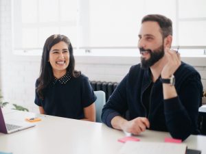 two colleagues smiling and laughing together in office, gender equality